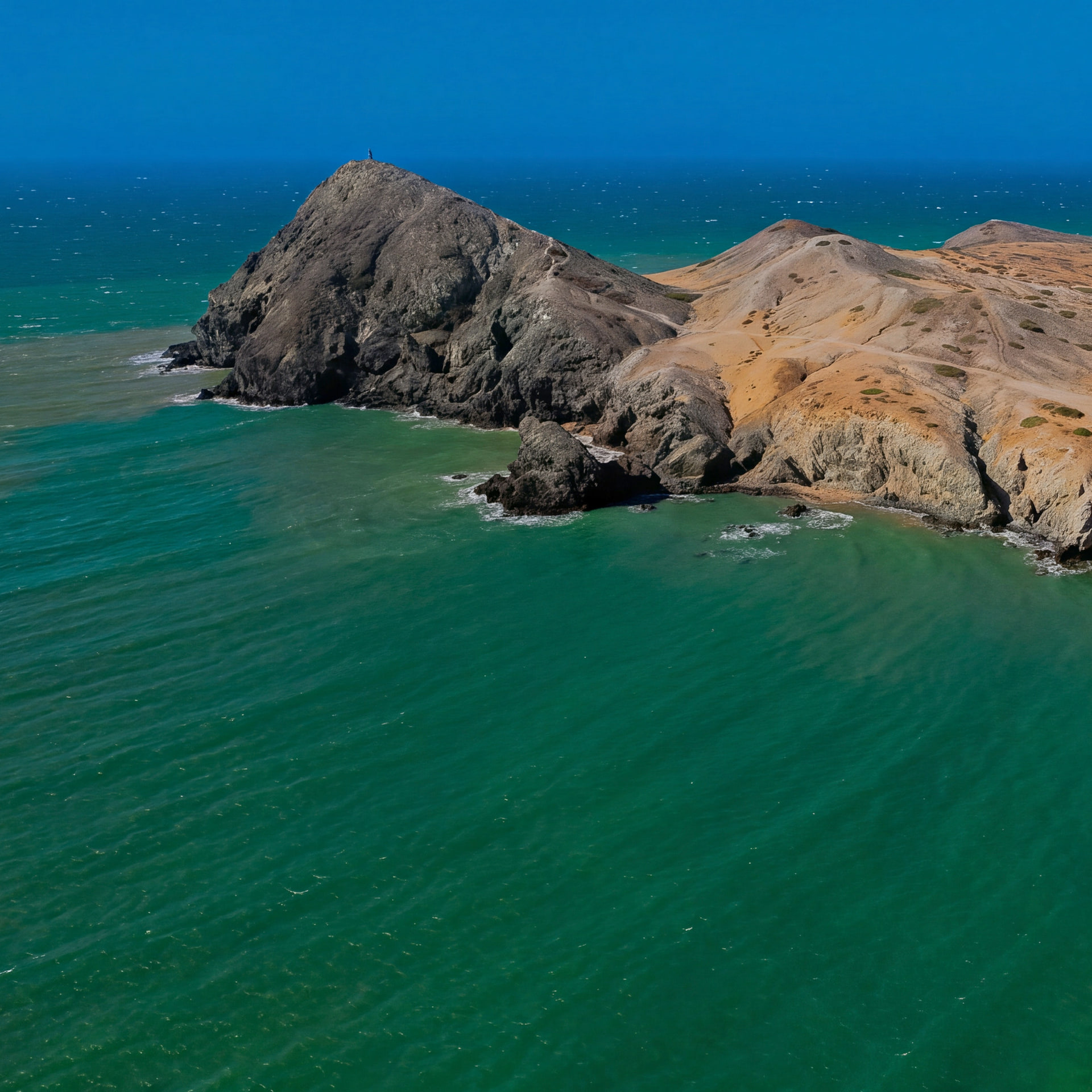 Vista aérea del Pilón de Azúcar, un cerro de roca junto al mar verde, con la playa del Pilón a la derecha, en el Cabo de la Vela (La Guajira).