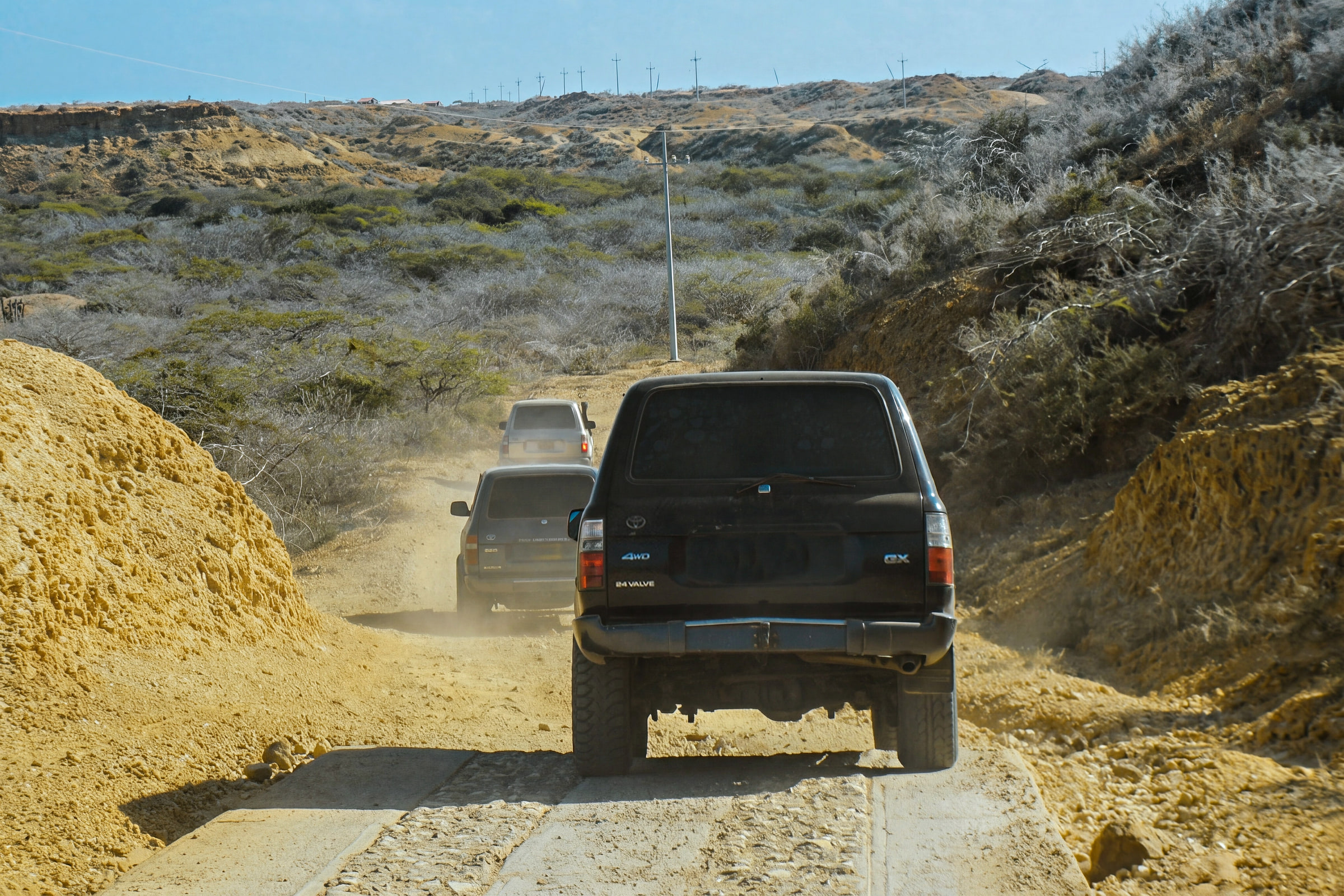 Three 4×4 vehicles in a row on a dirt track through dry scrub in Alta Guajira.