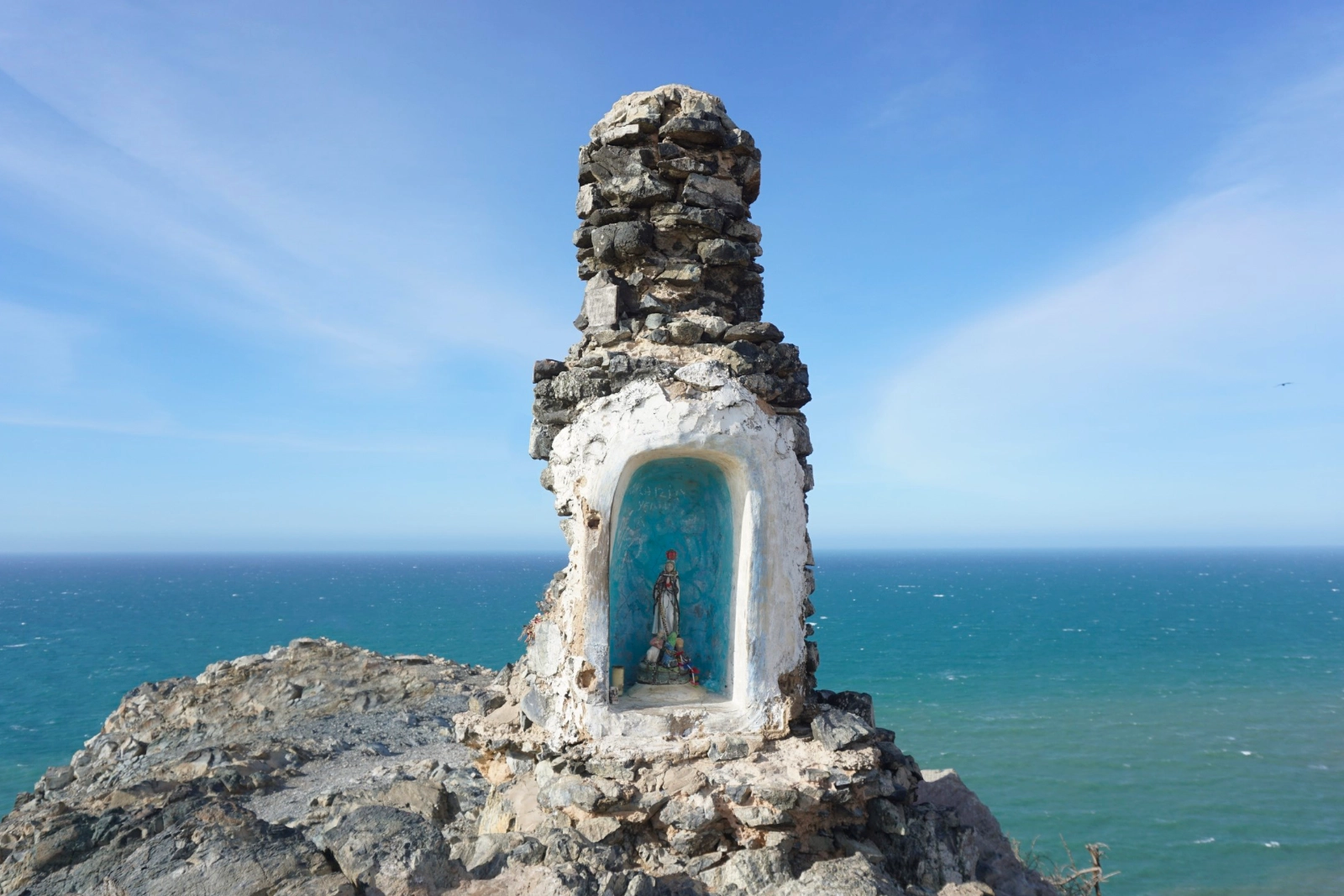 Autel en pierre blanchie à la chaux abritant une statue de la Vierge dans une niche, au sommet rocheux du Pilón de Azúcar, face à la mer.