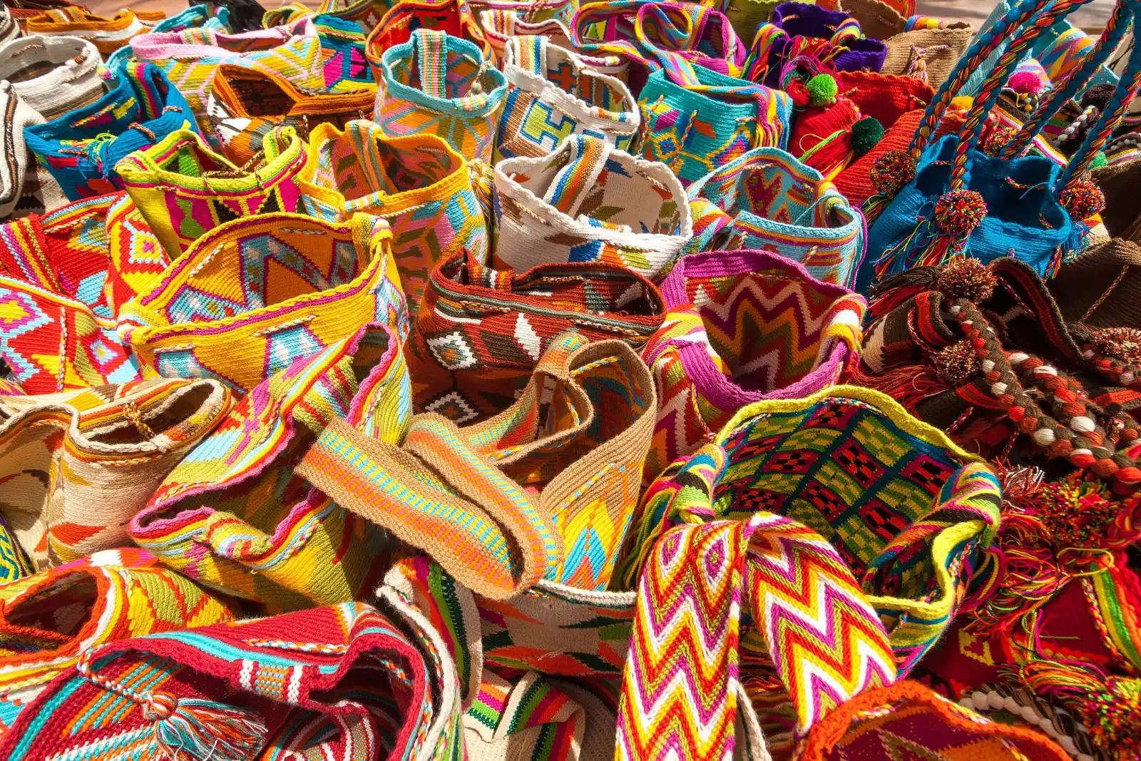 Mochilas wayuu (sacs) tissées de couleurs vives aux motifs géométriques, empilées les unes sur les autres et vues de près.